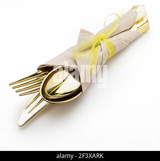 Goldenes Besteck (Messer, Gabel und Löffel) mit Serviette und Bogen. Bereit für ein Picknick. Isoliert auf weißem Hintergrund. Stockfoto