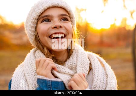 Lächelndes Mädchen in gestrickten Hut und Schal zu Fuß in der Herbstpark Stockfoto