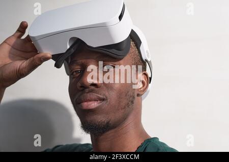 Nahaufnahme eines afrikanischen Mannes, der eine Brille aufsetzt und anschaut Kamera auf weißem Hintergrund isoliert Stockfoto