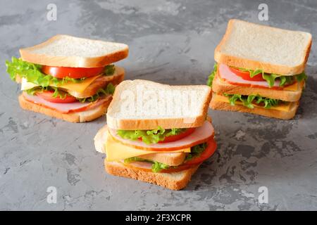 Drei leckere Sandwiches auf grauem Hintergrund Stockfoto