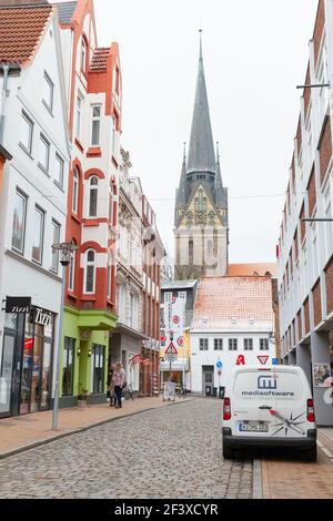 Flensburg, Deutschland - 9. Februar 2017: Vertikales Straßenbild der Flensburger Altstadt mit der Nikolaikirche. Gewöhnliche Menschen gehen die Straße entlang Stockfoto