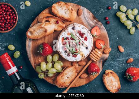 Romantische Dattsnacht. Valentinstag, Liebeskonzept. Gebackenen Camembert Käse, Honig, Rucola, Preiselbeere, Wein, Geröstetes Brot, Traube, Erdbeeren, Mandel Stockfoto