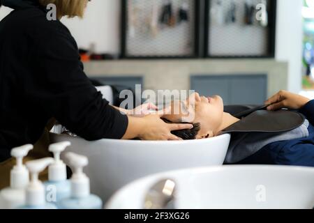 Friseur Anwendung Shampoo und massieren Haar eines Kunden. Mann, der ihr Haar in einem Friseursalon gewaschen. Stockfoto