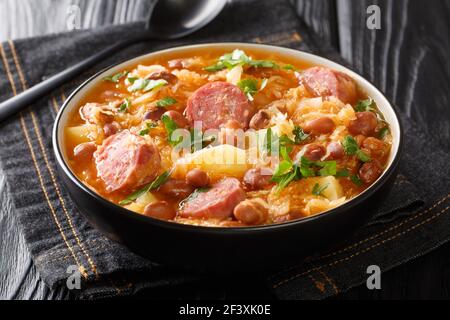 Hausgemachte Sauerkrautsuppe mit Borlotti-Bohnen, Kartoffeln und Würstchen in einer Schüssel auf dem Tisch. Horizontal Stockfoto