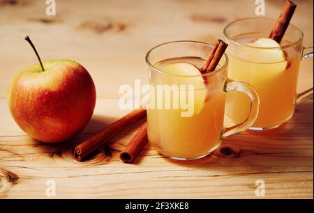 Hausgemachter Apfelwein in einer Glasschale mit Zimt und Eine Apfelscheibe auf einem Holztisch Stockfoto