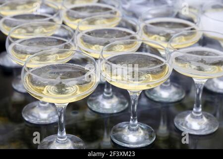 Gläser mit weißem Sekt, Champagner spiegeln sich in Glastisch. Konzept der Feier, Abendgesellschaft, Empfang Stockfoto