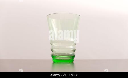 Einzelner grüner Glas-Becher im Art-Deco-Stil gegen weiche Blässe Hintergrund Stockfoto