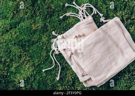 Mesh und Baumwollbeutel mit auf grünem Gras, Moos Hintergrund. Draufsicht. Nachhaltiger ökologischer Lebensstil. Zero Waste Konzept. Kein Kunststoff. Kunststoff frei Stockfoto