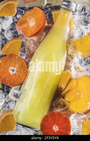 Eine Flasche sommerfrische Limonade in Wasser mit Eiswürfeln und Scheiben von Orangen und Früchten. Flach legen Wassertropfen. Stockfoto