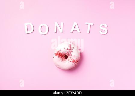 Süße Donuts mit Glasur und Text Donuts auf pastellrosa Hintergrund. Draufsicht. Speicherplatz kopieren. Kein Diät-Konzept. Stockfoto