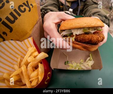 New York, USA. März 2021, 17th. Ein Diner bereitet das Mittagessen auf einem McDonald's Crispy Chicken Sandwich Deluxe zu, während er am Mittwoch, 17. März 2021, im Freien in New York zu Abend gegessen hat. Im Jahr 2019 Popeye's debütierte seine Huhn-Sandwich zu großem Erfolg führt fast jede Fast-Food-Kette zu einem knusprigen Huhn Menüelement zu generieren. McDonald's ist schließlich als 800-Pfund-Gorilla eingestiegen und hat bereits zu einer Steigerung des Fußgängerverkehrs in seinen Restaurants geführt. (ÂPhoto von Richard B. Levine) Quelle: SIPA USA/Alamy Live News Stockfoto