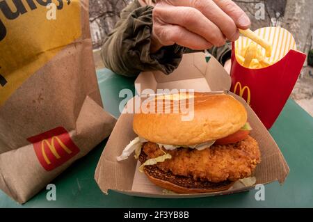 New York, USA. März 2021, 17th. Ein Diner bereitet das Mittagessen auf einem McDonald's Crispy Chicken Sandwich Deluxe zu, während er am Mittwoch, 17. März 2021, im Freien in New York zu Abend gegessen hat. Im Jahr 2019 Popeye's debütierte seine Huhn-Sandwich zu großem Erfolg führt fast jede Fast-Food-Kette zu einem knusprigen Huhn Menüelement zu generieren. McDonald's ist schließlich als 800-Pfund-Gorilla eingestiegen und hat bereits zu einer Steigerung des Fußgängerverkehrs in seinen Restaurants geführt. (ÂPhoto von Richard B. Levine) Quelle: SIPA USA/Alamy Live News Stockfoto