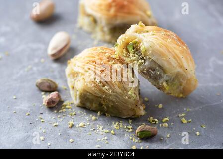 Baklava mit Pistazien auf grauem Hintergrund. Jüdische, türkische, arabische traditionelle nationale Dessert. Makro. Selektiver Fokus. Speicherplatz kopieren. Süßes aus dem Osten Stockfoto