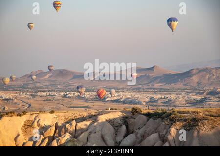 Türkei, Kappadokien, Goreme, 1. August 2019. Bunte Luftballons am Himmel über sandigen Bergen Stockfoto