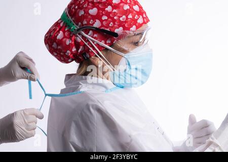 Die Hände des Gesundheitshelfer in Schutzhandschuhen helfen Eine Ärztin, die ein PSA-Set trägt Stockfoto
