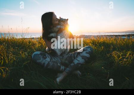 Nettes Mädchen küsst ihre schöne lustige schöne Katze im Freien bei Sonnenuntergang. Katze mit Besitzer. Liebe für Katzen. Stockfoto