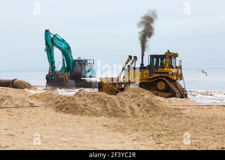 Bournemouth, Dorset, Großbritannien. März 2021, 18th. Am Strand von Bournemouth wird der Sand von einem Bagger durch Rohre aus dem Meer auf die Strandküste gepumpt. Mit mehr Menschen wahrscheinlich zu bleiben in diesem Jahr und Urlaub in Bournemouth die goldenen Sandstrände sind Teil der Attraktion. Ovenden SK500 und Cat Caterpillar D7H Series II Bagger - Wasser und Sand werden ausgepumpt und sprudeln. Quelle: Carolyn Jenkins/Alamy Live News Stockfoto