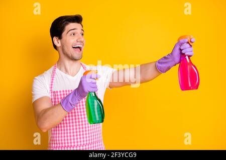 Profil Seite Foto von jungen glücklich aufgeregt lächelnden Mann aussehen Copyspace halten Reinigungsspray isoliert auf gelbem Hintergrund Stockfoto