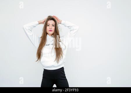 Schöne junge Frau, die über der weißen Wand steht Stockfoto