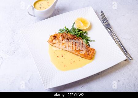 Lachs mit Beurre Blanc Sauce, Spinat und Zitrone. Garniert mit Lauch. Traditionelles französisches Gericht. Nahaufnahme. Stockfoto