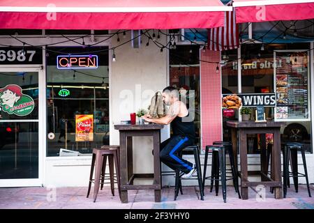 Miami Beach, USA - 5. Mai 2018: Mann sitzt draußen am Tisch, Stühle in lokalen mexikanischen Bürgersteig Restaurant Bar Café serviert Pizza Empanadas, ch Stockfoto