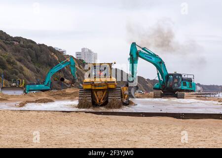 Bournemouth, Dorset, Großbritannien. 18th. März 2021. Am Strand von Bournemouth wird der Sand von einem Bagger durch Rohre aus dem Meer auf die Strandküste gepumpt. Mit mehr Menschen wahrscheinlich zu bleiben in diesem Jahr und Urlaub in Bournemouth die goldenen Sandstrände sind Teil der Attraktion. Ovenden SK500 und Cat Caterpillar D7H Series II Bagger Credit: Carolyn Jenkins/Alamy Live News Stockfoto