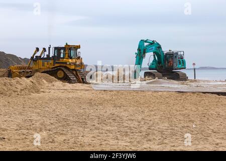 Bournemouth, Dorset, Großbritannien. 18th. März 2021. Am Strand von Bournemouth wird der Sand von einem Bagger durch Rohre aus dem Meer auf die Strandküste gepumpt. Mit mehr Menschen wahrscheinlich zu bleiben in diesem Jahr und Urlaub in Bournemouth die goldenen Sandstrände sind Teil der Attraktion. Ovenden SK500 und Cat Caterpillar D7H Series II Bagger - Wasser und Sand werden ausgepumpt und sprudeln. Quelle: Carolyn Jenkins/Alamy Live News Stockfoto