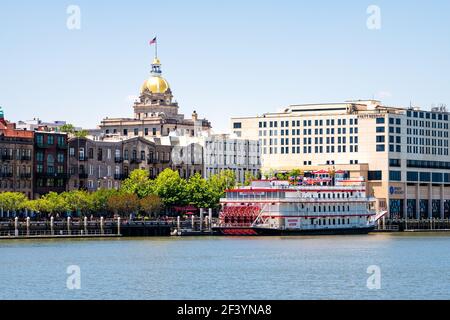 Savannah, USA - 11. Mai 2018: Flussstraße Altstadt Waterfront von Georgia Queen Dampfschiff Kreuzfahrtschiff, Golden Dome Rathaus und Hyatt Regency Hotel c Stockfoto