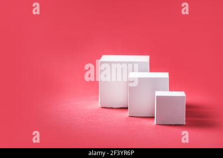 Abstrakte leere geometrische Form Podium für Produkt auf pastellrotem Hintergrund. Speicherplatz kopieren. Weißer Würfel auf rosa Hintergrund. Standvorlage für Werbung Stockfoto
