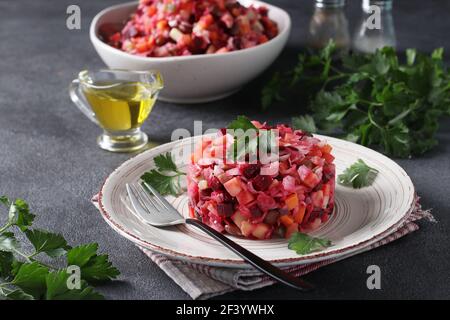 Traditionelle Salat Vinaigrette von Rüben, Kartoffeln, Karotten, Bohnen, Gurken, Zwiebeln und Pflanzenöl auf dunkelgrauem Hintergrund. Vegetarisches Essen Stockfoto