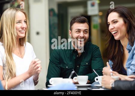 Multirassische Gruppe von Freunden, die einen Kaffee zusammen. Zwei Frauen und ein Mann im Café, reden, lachen und genießen ihre Zeit. Lifestyle- und Freundschaftskonzepte mit echten Menschen-Modellen Stockfoto