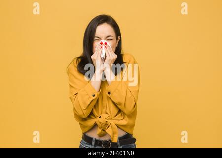 Foto von kranken Weibchen niesen. Trägt gelbes Hemd, isolierte gelbe Farbe Hintergrund Stockfoto