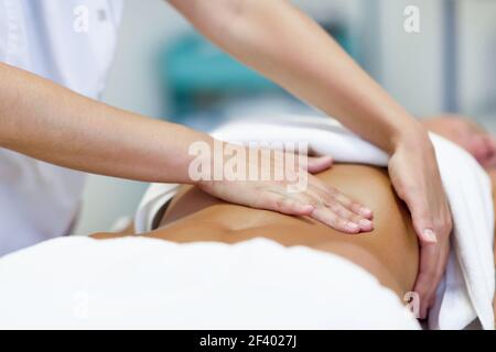 Frau mit Abdomen Massage durch professionelle Osteopathie therapis. Die Patientin wird von einem professionellen Osteopathietherapeuten behandelt. Frau mit Abdomen Massage in einem Physiotherapie-Zentrum. Stockfoto