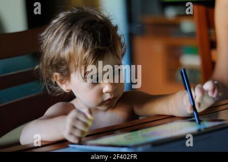 Kleines Mädchen, zwei Jahre alt, Malen mit einem digitalen Tablette zu Hause. Stockfoto