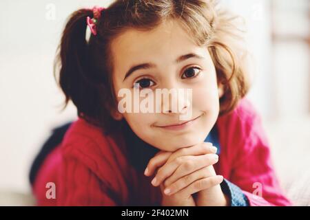 Adorable kleine Mädchen mit süßen Lächeln liegend auf dem Bett. Close-up Portrait. Stockfoto