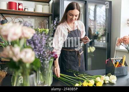 Foto von erfolgreichen modernen Floristen tragen Schürze, die Schaffung schöner Strauß von bunten verschiedenen Blumen in modernen Innenarchitektur floral Shop Stockfoto