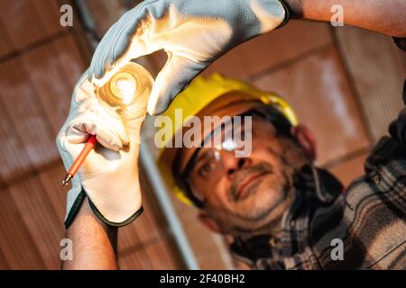 Elektriker bei der Arbeit ersetzt die Glühbirne in einer elektrischen Wohnanlage. Bauindustrie, Energiesektor. Stockfoto