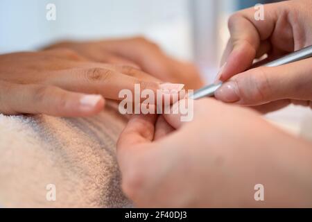 Frau mit verschlechtert Nägel in einem Salon empfangen einer Maniküre durch eine Kosmetikerin mit Nagelfeile. Stockfoto