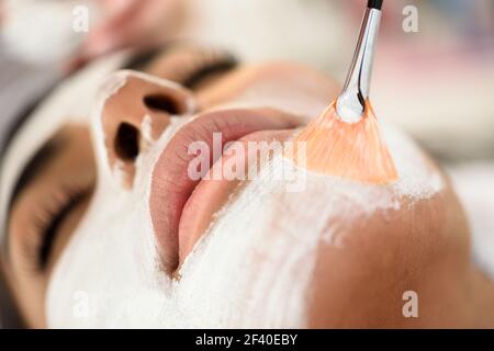 Ästhetik Anwenden einer Maske auf das Gesicht einer schönen Frau in modernes Wellnesscenter. Schönheit und ästhetische Konzepte. Stockfoto