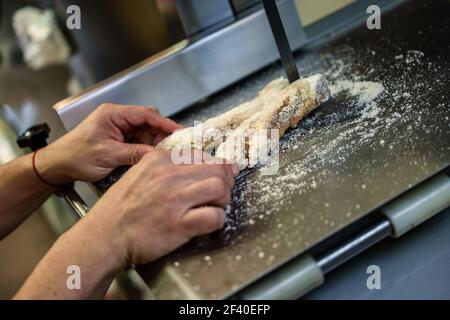 Nahaufnahme der männlichen Metzger schneiden Schinken Knochen in einer Maschine in einer Metzgerei. Stockfoto