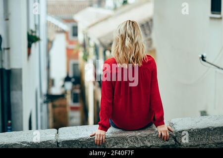 Junge blonde touristische Frau sitzt im Freien suchen eine schöne Gasse in Granada, Andalusien, Spanien Stockfoto