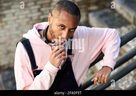 Junge schwarze Mann legere Kleidung auf städtischen Schritte. Schweren afrikanischen Kerl mit Latzhose im Freien Stockfoto