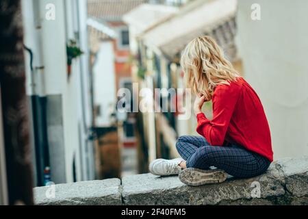 Junge blonde touristische Frau sitzt im Freien suchen eine schöne Gasse in Granada, Andalusien, Spanien Stockfoto