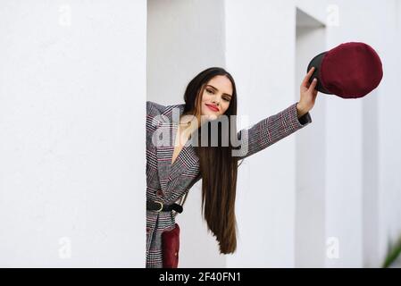 Spanien, Andalusien, Granada. Junge schöne Mädchen mit sehr langen Haaren Blick auf Kamera tragen Wintermantel und Mütze im Freien. Lifestyle- und Modekonzept. Stockfoto