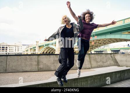 Lustiges Paar, das in der Nähe der Southwark Brücke über die Themse, London, junping. VEREINIGTES KÖNIGREICH. Lustiges Paar, das in der Nähe der Southwark Brücke über die Themse, London, junping Stockfoto