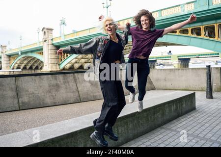 Lustiges Paar, das in der Nähe der Southwark Brücke über die Themse, London, junping. VEREINIGTES KÖNIGREICH. Lustiges Paar, das in der Nähe der Southwark Brücke über die Themse, London, junping Stockfoto