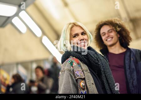 Junges Paar mit lockigen Haaren, das an einer U-Bahn-Station nach oben geht. Moderne Mann und Frau in lässiger Kleidung.. Junges Paar, das an einer U-Bahnstation die Treppe rauf geht. Stockfoto