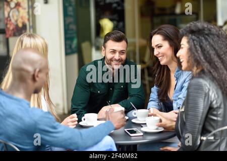 Multirassische Gruppe von fünf Freunden mit einem Kaffee zusammen. Drei Frauen und zwei Männer im Café, reden, lachen und genießen ihre Zeit. Lifestyle- und Freundschaftskonzepte mit echten Menschen-Modellen. Multirassische Gruppe von fünf Freunden mit einem Kaffee zusammen Stockfoto