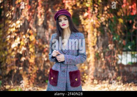 Junge schöne Frau mit sehr langen Haaren tragen Wintermantel und Mütze im Herbst Blätter Hintergrund. Lifestyle und Mode Konzept.. Junge schöne Frau mit sehr langen Haaren tragen Wintermantel und Mütze im Herbst Blätter Hintergrund Stockfoto