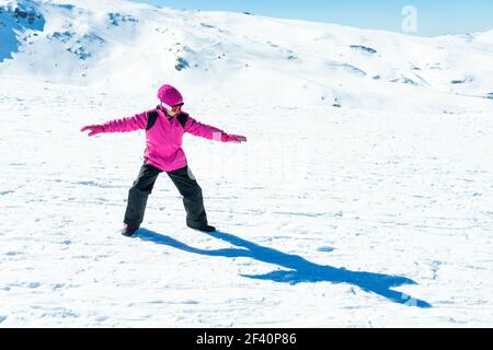 Kleines Mädchen, das Snowboardtrainer auf Schnee in Sierra Nevada Ski-Resort in Schnee-Kleidung.. Kleine Mädchen spielen Snowboard-Trainer auf Schnee Stockfoto